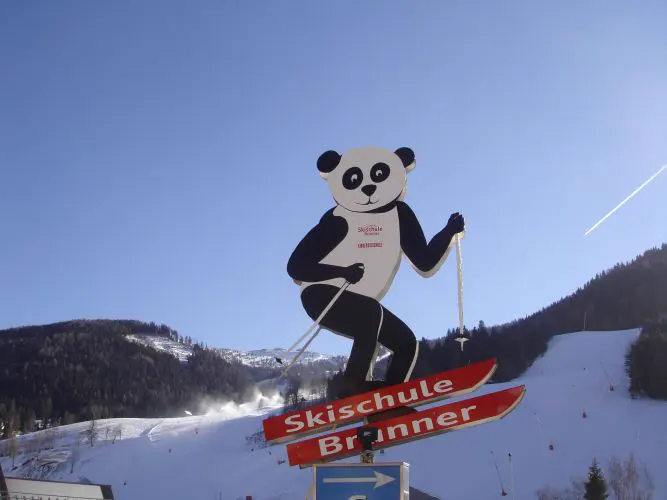 Panda-Schild der Skischule Brunner über dem Tal